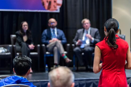 Woman asks question to a panel of presenters